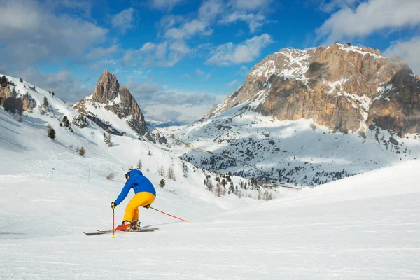 意大利多洛米蒂地区 一名身穿蓝色和黄色衣服的男子滑雪者在山坡上滑行 背景是山脉 — 图库照片