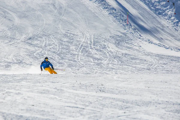 Sciatore Maschile Abiti Blu Gialli Pista Con Montagne Sullo Sfondo — Foto Stock