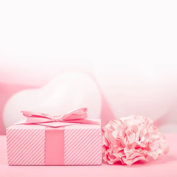 情人节礼物装在一个盒子里 盒子里用条纹纸包着 用丝带 蝴蝶结和心形贺卡捆着 背景是粉色气球 上面有文字复制空间 — 图库照片
