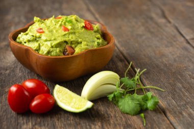 Tahta bir arka planda taze malzemeyle geleneksel Meksika guacamole kasesini kapat. 