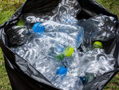 Siyah çöp torbalarındaki plastik şişeler geri dönüşüm için alınmayı bekliyor..