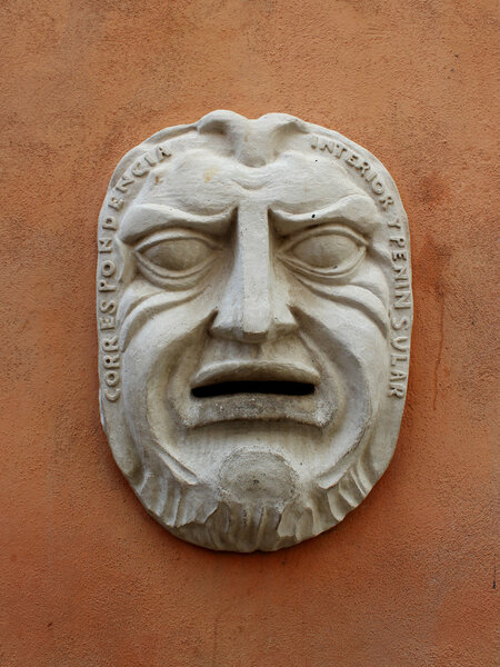 Древняя маска на стене здания
