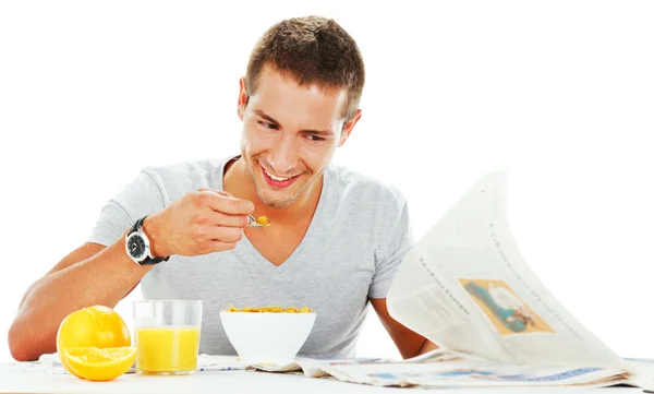 Happy young man reading newspaper while having energetic breakfa — Stock Photo, Image