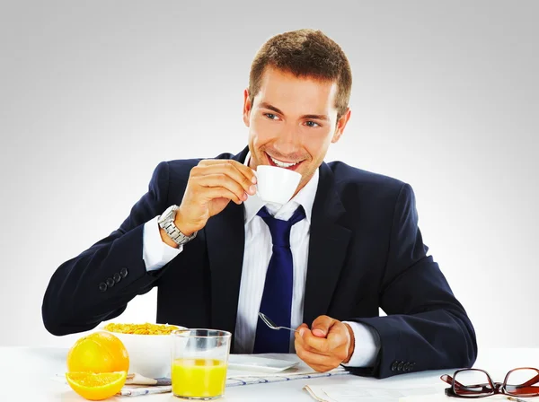 Happy businessman having breakfast at office — Stock Photo, Image