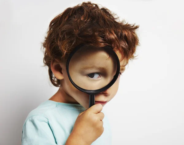 Boy looking through a magnifying glass — Stock Photo, Image