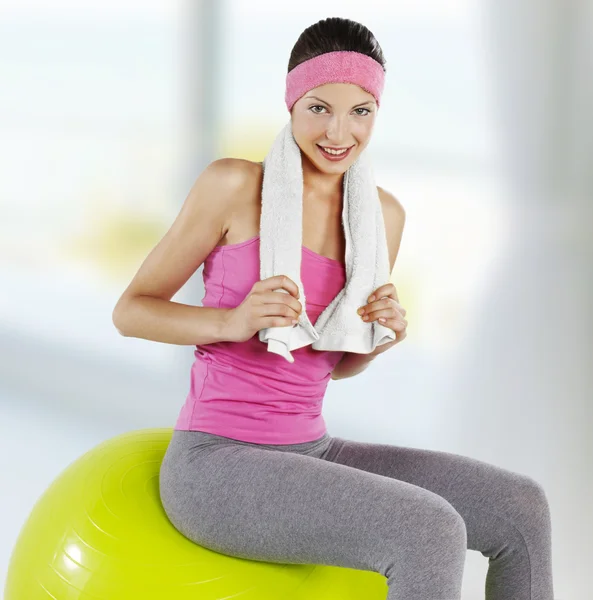 Fitness young woman with towel around her neck smiling — Stock Photo, Image