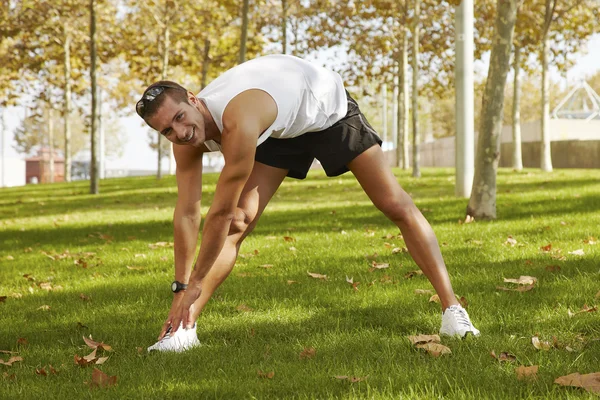 Sportmann dehnt sich im Park - Fitnesskonzepte — Stockfoto