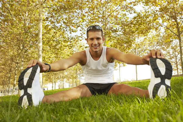 Sportovní muž táhnoucí se v parku - fitness pojmy — Stock fotografie