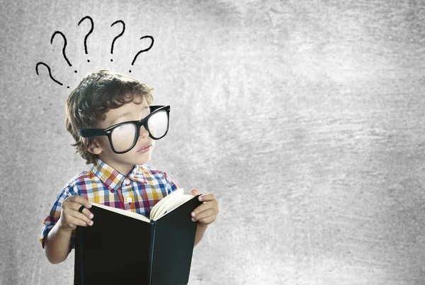 Niño con un libro buscando respuestas — Foto de Stock