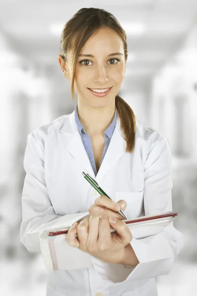 Woman doctor writing a medical history at the hospital — Stock Photo, Image
