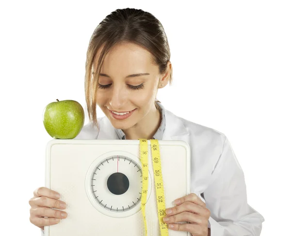 Ernährungsberater beobachtet und hält eine Gewichtswaage und grünen Apfel in der Hand — Stockfoto