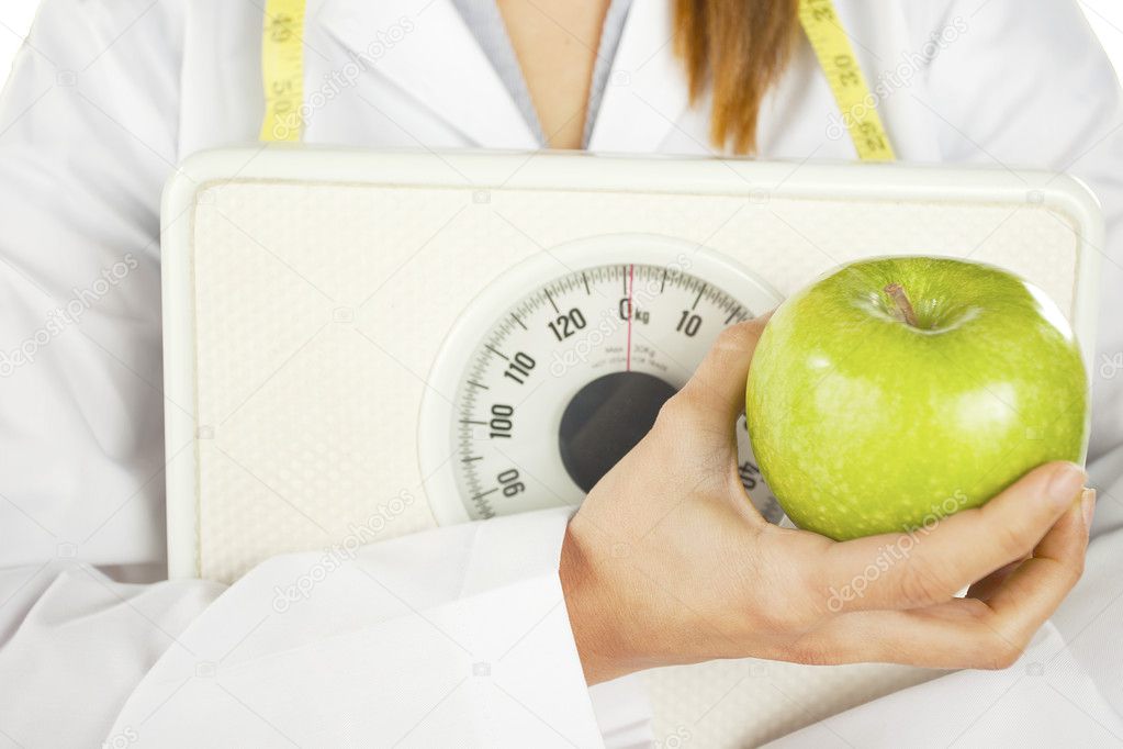 Nutritionist holding a green apple and weight scale