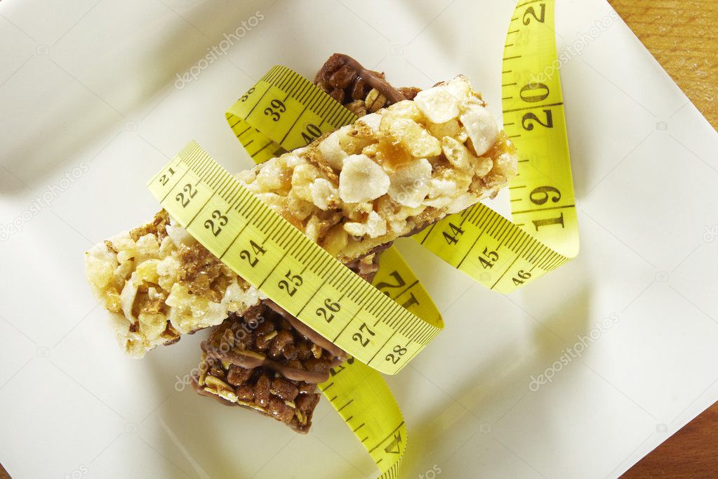 Cereals and chocolate bars with measuring tape in a dish