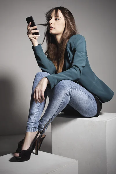 Ung affärskvinna sitter och tittar på en smart telefon — Stockfoto