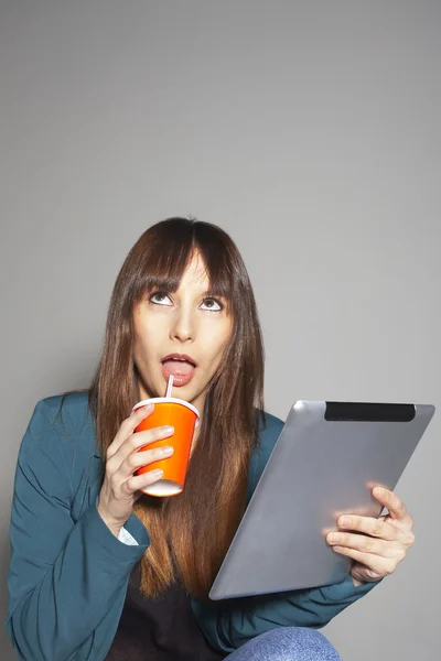 Joven mujer de negocios mirando hacia arriba y beber refresco con tableta digital —  Fotos de Stock