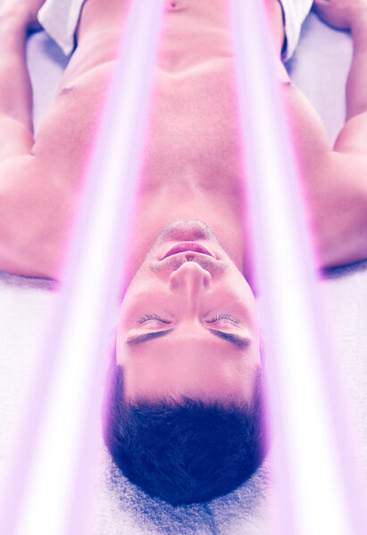 Young man have tanning skin treatment in modern solarium