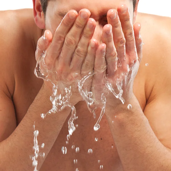 Jonge man sproeien van water op zijn gezicht na het scheren in de badkamer — Stockfoto