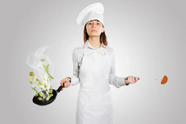 Σοβαρό μάγειρα γυναίκα που κρατά ένα τηγάνι με δημιουργική κουζίνα — Φωτογραφία Αρχείου