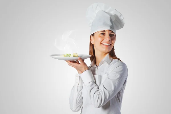 Mulher cozinheira feliz segurando um prato — Fotografia de Stock