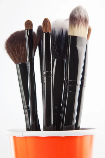 Cosmetic brushes in orange cup — Stock Photo, Image