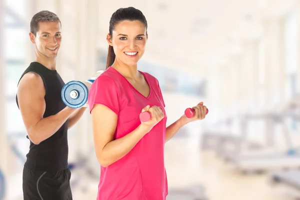 Young couple exercising with weights together in the gym — Stock Photo, Image