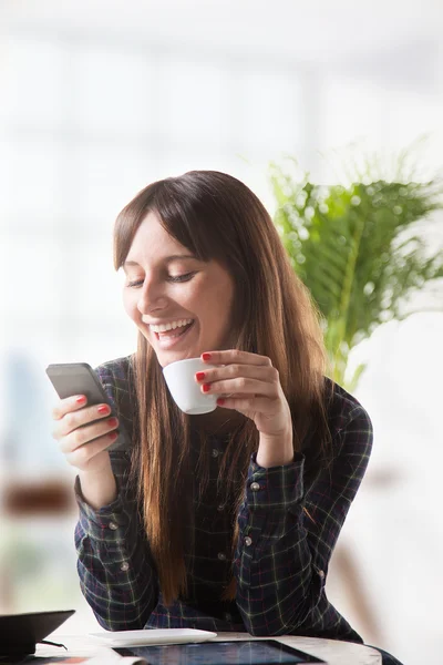 コーヒーと送信メッセージを持つ若い女性の笑みを浮かべてください。 — ストック写真