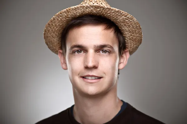 Portrait of a normal young man with straw hat on a grey background — Stock Photo, Image