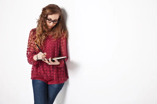 Kvinnlig student skriver på anteckningsboken — Stockfoto