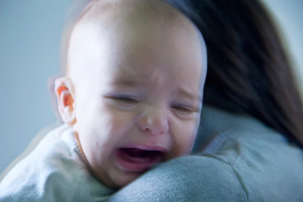 Bambino piccolo che piange tra le braccia della madre — Foto Stock