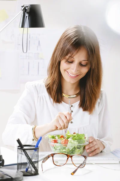 Joven diseñadora creativa comiendo una ensalada en la oficina . — Foto de Stock