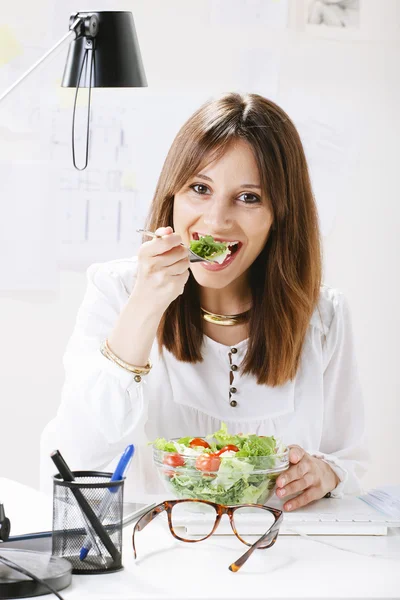 Genç kadın yaratıcı tasarımcı ofisinde bir salata yemek. — Stok fotoğraf