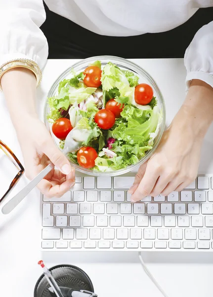 Jeune créatrice mangeant une salade tout en travaillant au bureau . — Photo