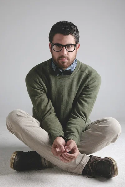 Stylish young man wearing bowtie sitting at floor on grey Background. — Stock Photo, Image