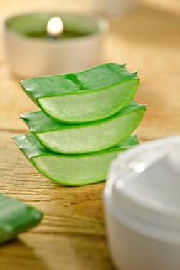 taze aloe vera dilimleri ve ahşap üzerine krem konteyner.