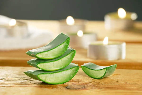 Frische Aloe Vera Scheiben auf Holz mit ein paar Kerzen. — Stockfoto