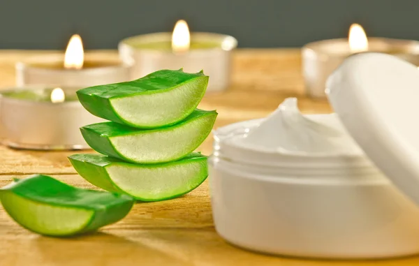 Fresh aloe vera slices and cream container on wooden. — Stock Photo, Image