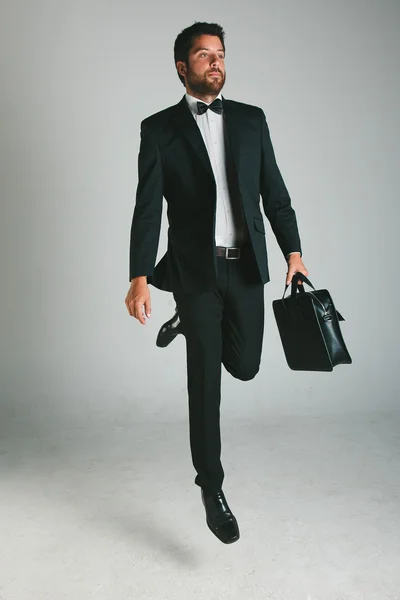 Elegante giovane uomo con abito nero e valigetta . — Foto Stock