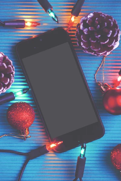 Slimme telefoon en kerst decoratie op blauwe achtergrond. — Stockfoto