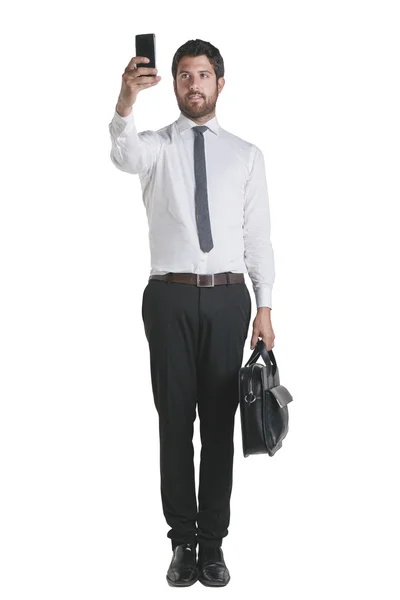 Молодой бизнесмен стоит с портфелем и работает со смартфоном . — стоковое фото