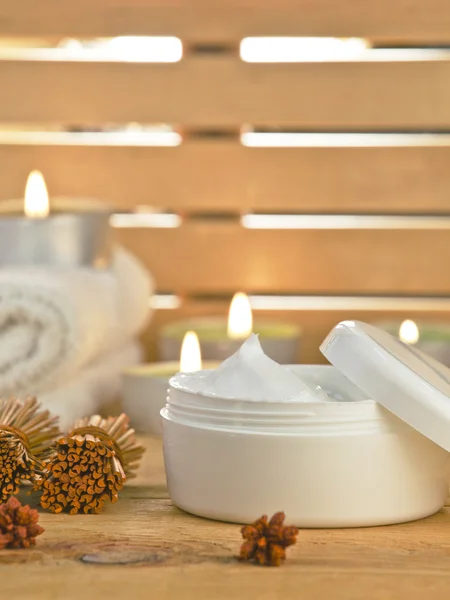 Cosmetic cream product with candles on wooden.