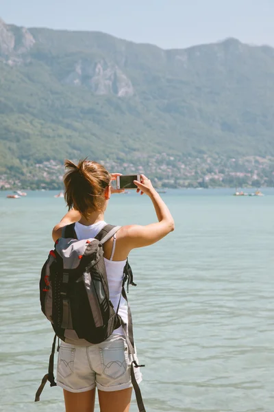 Vista posterior de la mujer joven tomando fotos con el teléfono móvil . —  Fotos de Stock