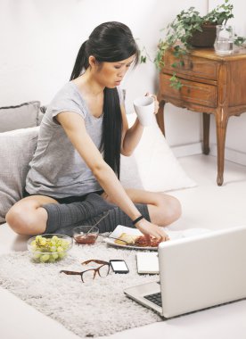 Casual asian woman having breakfast and working in home. clipart