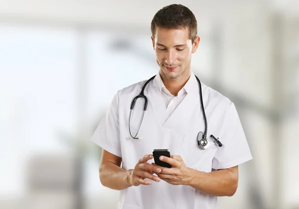 Jeune médecin homme avec stéthoscope envoyant un message à l'hôpital . — Photo