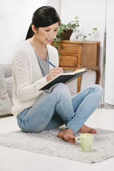 Lässige asiatische Frau sitzt auf dem Boden und arbeitet zu Hause. — Stockfoto