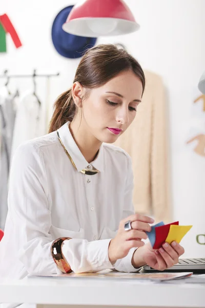 Mode vrouw blogger in een creatieve werkruimte kiezen van kleuren. — Stockfoto