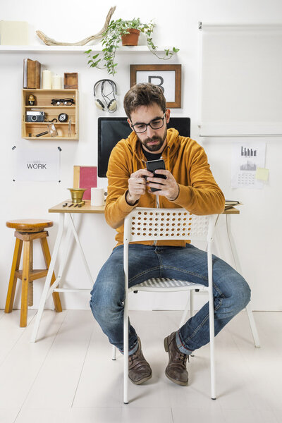 Modern creative man with smartphone on workspace.