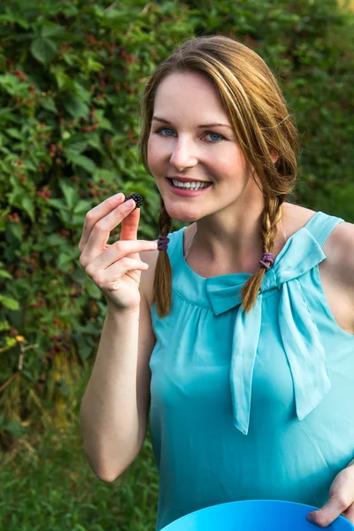 Frau im blauen Kleid isst Brombeeren — Stockfoto