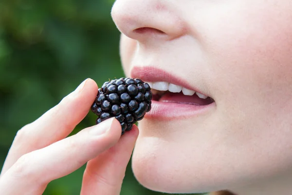 Kvinna sätta blackberry i munnen Stockbild