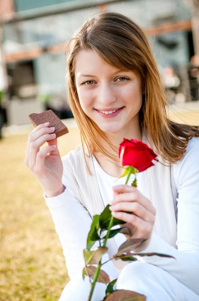 Молода жінка з червоною трояндою і шоколадом — стокове фото