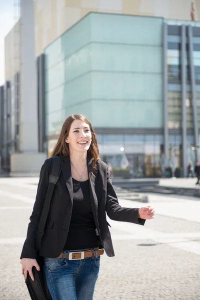 Mujer joven con el bolso del ordenador portátil caminando calle — Foto de Stock